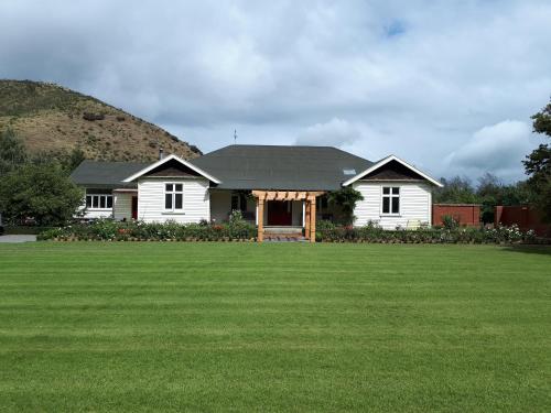 a white house with a large grass yard at Hurunui Homestead Bed and Breakfast in Hawarden