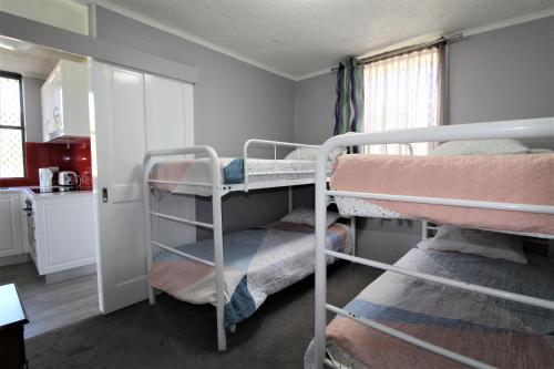 a room with two bunk beds and a kitchen at Beachfront 3, 25 Willow Street in Crescent Head