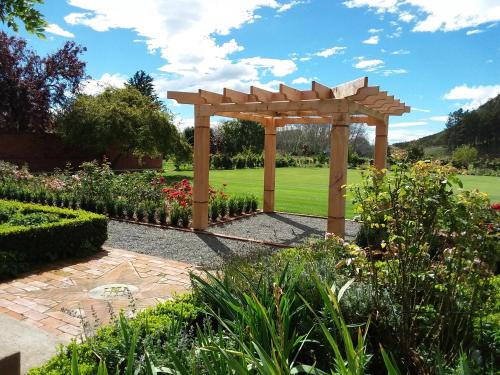 a wooden pergola in the middle of a garden at Hurunui Homestead Bed and Breakfast in Hawarden