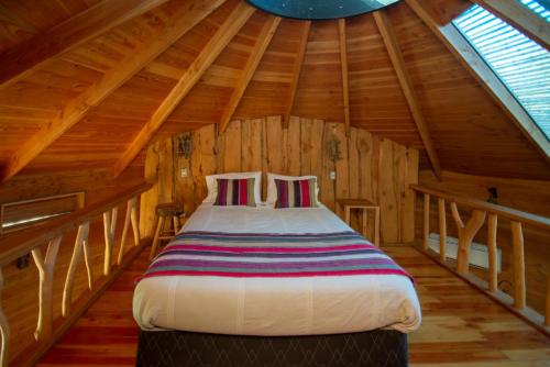 a bedroom with a bed in a wooden attic at Cabañas Agua Viva in Molco