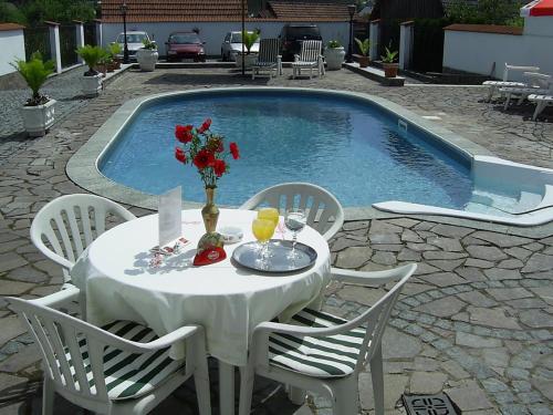 a white table with chairs next to a swimming pool at Pension Šejko in Horní Planá
