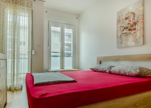 Schlafzimmer mit einem großen roten Bett und einem Fenster in der Unterkunft Zebra in Podgorica