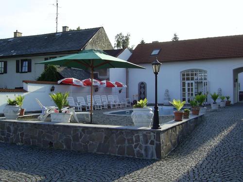 a patio with an umbrella and chairs and a pool at Pension Šejko in Horní Planá