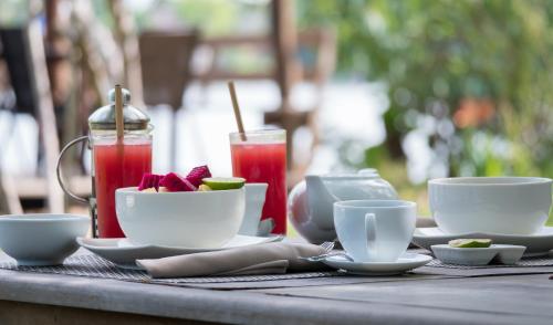 una mesa con tazas y platos de comida y bebida en Champa Lodge, en Kampot