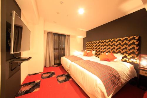 a hotel room with two beds and a television at Centurion Hotel Ikebukuro Station in Tokyo