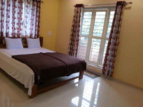a bedroom with a bed and a large window at Maharaja Home Stay Panhala in Panhāla