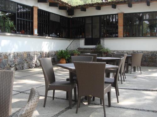 a patio area with chairs, tables, and tables with umbrellas at Rancho Hotel Atascadero in San Miguel de Allende
