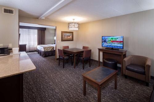 a hotel room with a dining table and a room with a bed at Best Western Ramkota Hotel in Rapid City