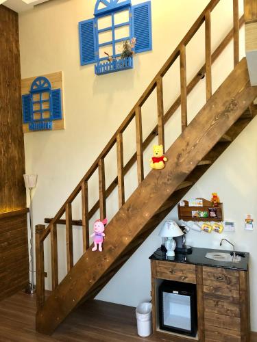 a room with a wooden staircase with blue windows at Puli Story House in Puli