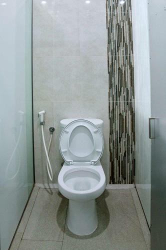 a bathroom with a toilet with a shower curtain at FixOn Capsule Hotel in Purwokerto
