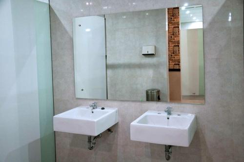 a bathroom with two sinks and a mirror at FixOn Capsule Hotel in Purwokerto