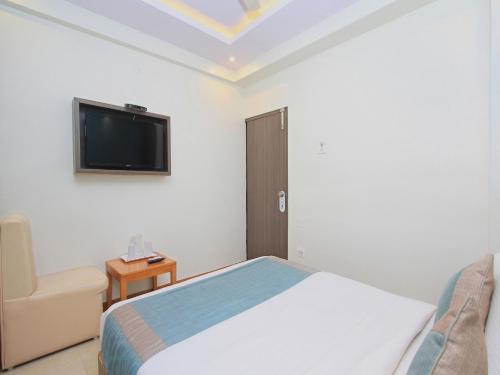 a bedroom with a bed and a tv and a chair at Aishwarya Le Royal in Mysore