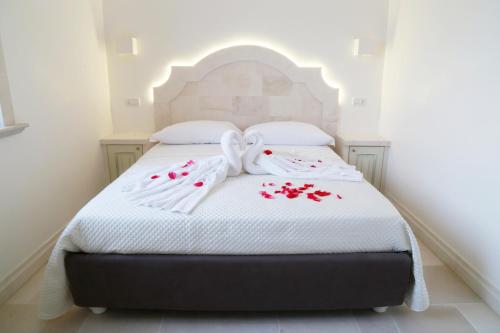 a bed with white sheets and red flowers on it at Villa Angelina in Selva di Fasano