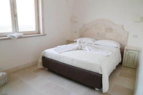 a bedroom with a bed with white sheets and two windows at Villa Angelina in Selva di Fasano