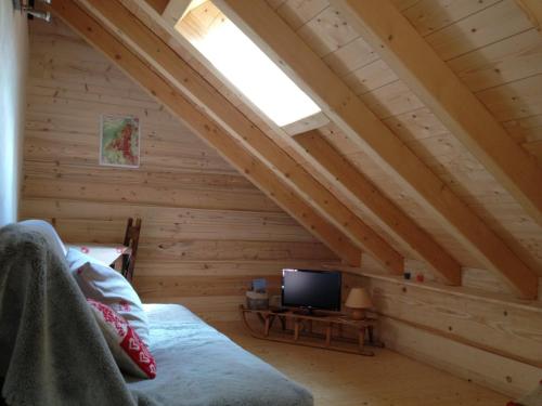 Zimmer mit einem Bett und einem TV im Dachgeschoss in der Unterkunft Au cœur du bois in Le Bouilly