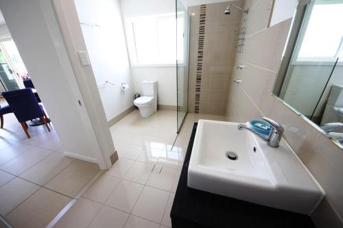 a white bathroom with a sink and a toilet at Geckos at South West Rocks in South West Rocks