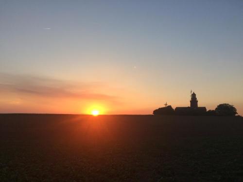 a sunset over a field with a lighthouse at Ferienresidenz Fürst von Büttelkow in Rerik