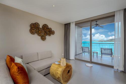 a living room with a couch and a view of the ocean at Cape Sienna Phuket Gourmet Hotel & Villas - SHA Extra Plus in Kamala Beach