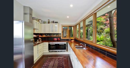 een keuken met een koelkast en een aantal ramen bij The Black Cockatoo - Secret Garden Treetops Home in Katoomba