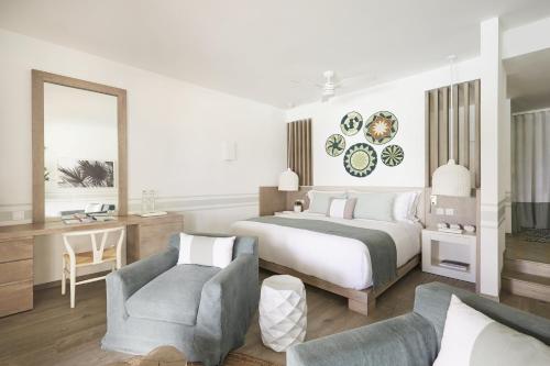 a bedroom with a bed and a desk and a chair at LUX* Grand Gaube Resort & Villas in Grand Gaube