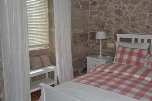 a bedroom with a bed and a stone wall at Casa tía Amparo in Portosin