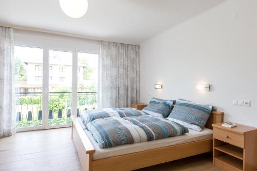a bedroom with a bed with blue pillows and a window at Apartements Kaschitz in Pörtschach am Wörthersee