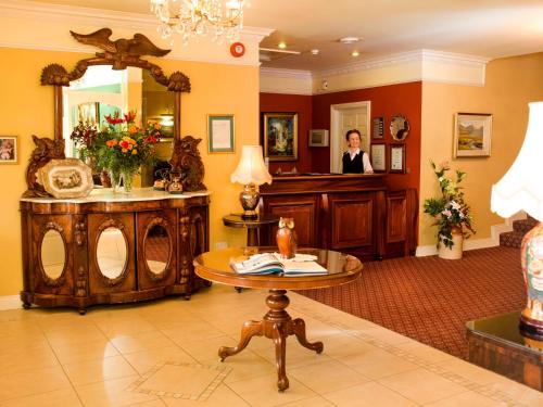 キラーニーにあるアールズ コート ハウスのテーブルと鏡のある部屋の女性