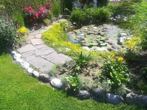 a garden with a pond with flowers and plants at Pension Leyrer in Kötschach
