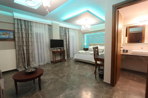 a living room with a bed and a room with a television at Hotel Mallas in Nea Kalikratia