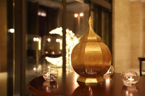 a golden vase sitting on a table with two glasses at Somewhere Hotel Al Ahsa in Al Hofuf