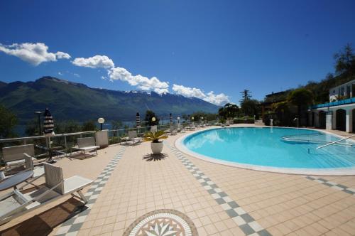 a large swimming pool with mountains in the background at Hotel Riviera Panoramic Green Resort in Limone sul Garda