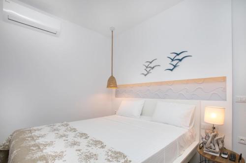 a bedroom with a white bed with a white headboard at Elenis Philoxenia in Ixia