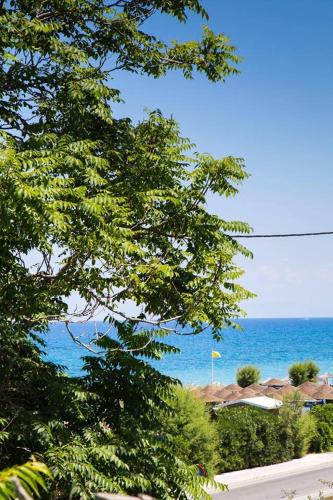 a view of the ocean from behind some trees at Elenis Philoxenia in Ixia