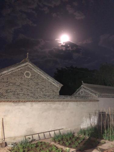 a full moon over a building at night at Chez Ina & Jasee in Miyun