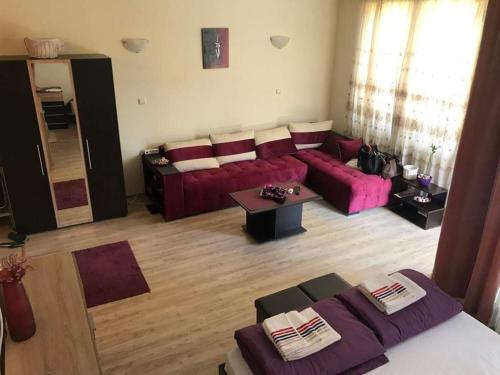 a living room with a red couch and a table at Nestinarka Complex - Emili Apartment in Tsarevo
