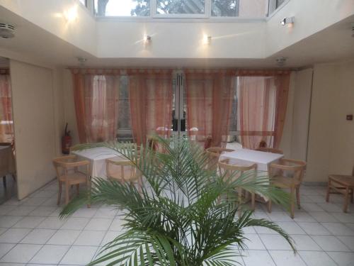 a restaurant with tables and chairs and a palm tree at Hotel Le Village in Gif-sur-Yvette