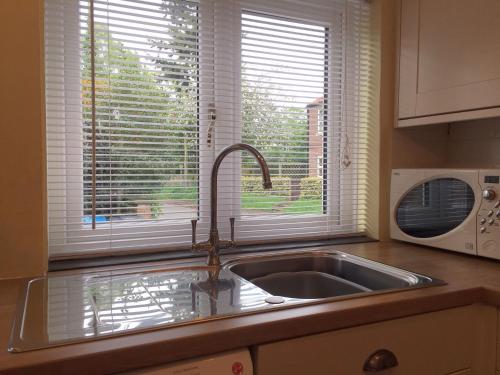 encimera de cocina con fregadero y ventana en Ceilidh Cottage en York