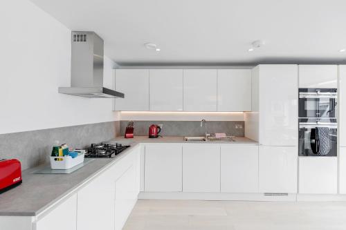 a white kitchen with white cabinets and a red appliance at Roomspace Serviced Apartments- Walpole Court in Ealing
