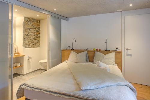 a bedroom with a large bed with white sheets at MyVerzasca Resort Ai piee in Brione