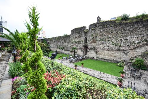 a garden in front of a stone wall at Real Scampis Hotel in Elbasan