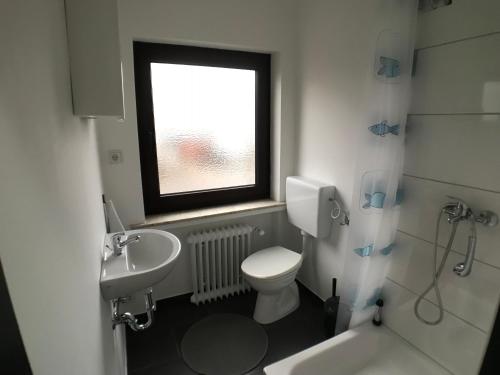 a bathroom with a toilet and a sink and a window at Living @ Klassvilla Weserwehr No. 3 in Bremen