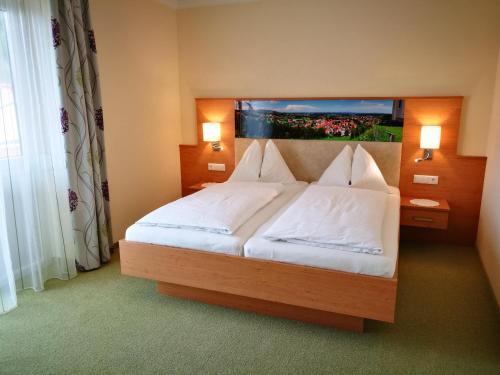 a bedroom with a large bed with white sheets and pillows at Hotel Restaurant zum Schwan in Schwanberg