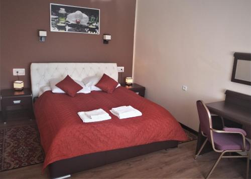 a bedroom with a red bed with two towels on it at Hotel Skarpa in Sejny