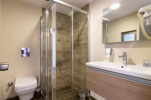 a bathroom with a shower and a toilet and a sink at The D Hotel Çeşme Resort in Çeşme