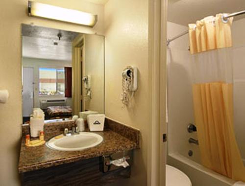 ein Badezimmer mit einem Waschbecken, einem WC und einem Spiegel in der Unterkunft Park Avenue Inn & Suites in Victorville