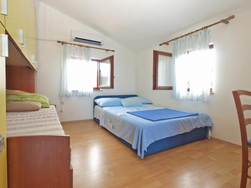 a bedroom with a blue bed and two windows at Apartments Milan 1665 in Peroj