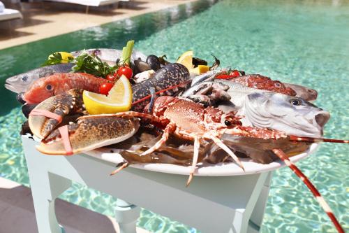 a plate of seafood on a table next to a pool at MUSE Saint Tropez - Small Luxury Hotels of the World in Saint-Tropez