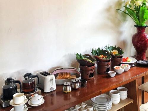une table en bois avec des pots de plantes et un grille-pain dans l'établissement Puri Langenarjan Guest House, à Yogyakarta