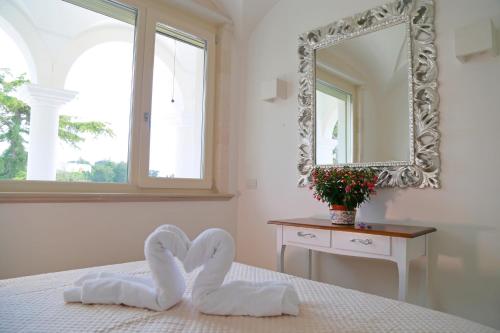 a bedroom with a mirror and a bed with towels at Villa Angelina in Selva di Fasano