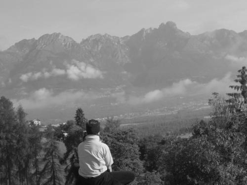 a man sitting on top of a hill looking at a mountain at Agriturismo La Casa Nei Boschi in Colderù